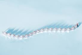 Lab-grown diamond tennis bracelet on blue background.