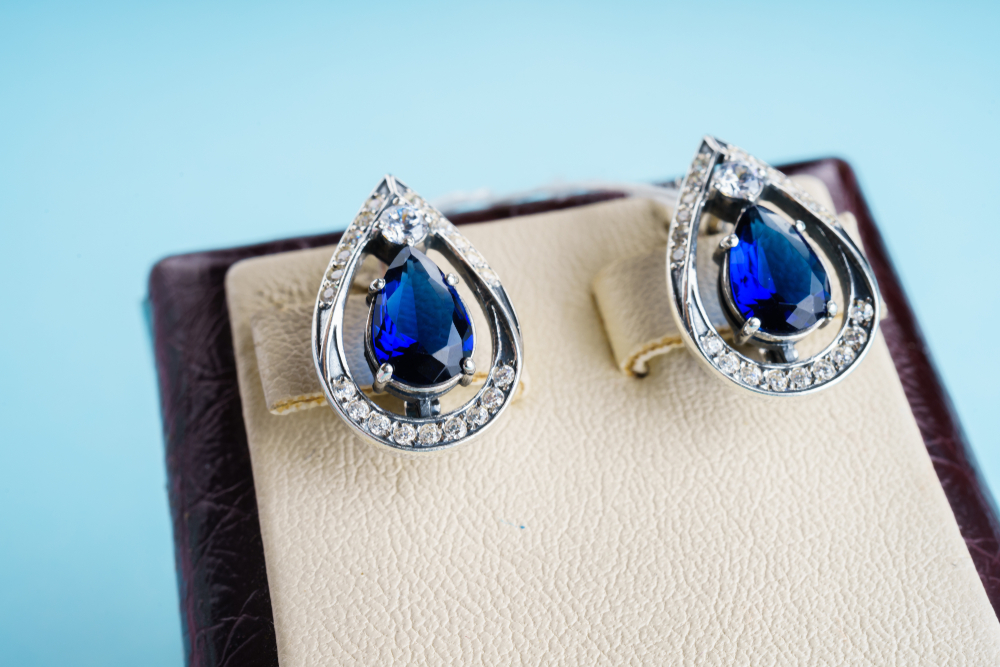 White gold pear shaped blue sapphire earrings with diamond haloes.