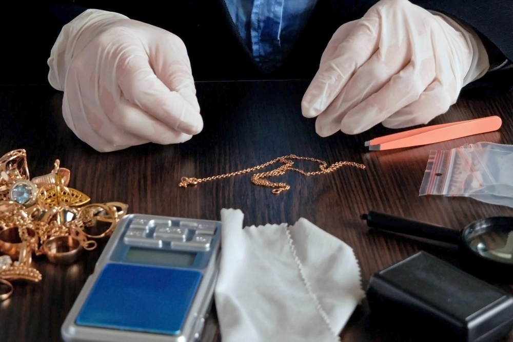 2 hands examining some jewelry on a wooden table