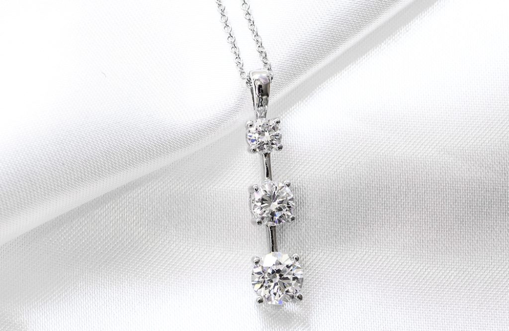 White gold three-station drop necklace set with cushion cut diamonds.